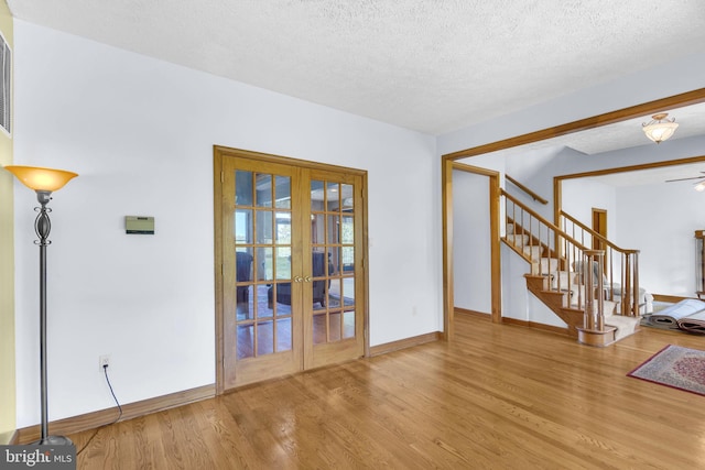 10150 Lapworth Pl, Charlotte Hall, MD 20622 - spare room featuring french doors, wood finished floors, baseboards, stairway, and a textured ceiling
