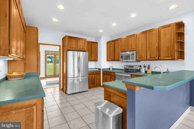 10150 Lapworth Pl, Charlotte Hall, MD 20622 - kitchen featuring appliances with stainless steel finishes, a peninsula, brown cabinets, a breakfast bar area, and open shelves