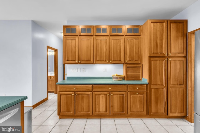 10150 Lapworth Pl, Charlotte Hall, MD 20622 - kitchen featuring brown cabinets, light tile patterned floors, glass insert cabinets, and baseboards