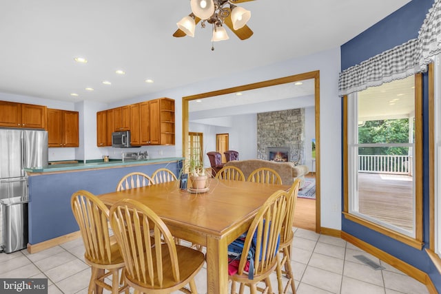 10150 Lapworth Pl, Charlotte Hall, MD 20622 - dining space with light tile patterned floors, ceiling fan, recessed lighting, a stone fireplace, and baseboards