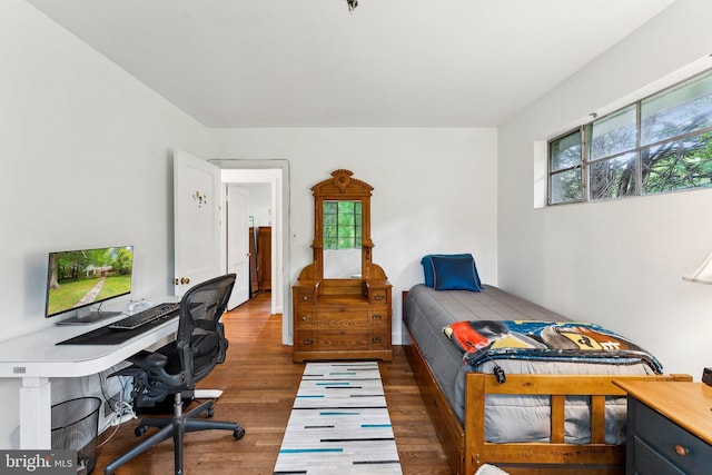 bedroom featuring wood finished floors and an office area