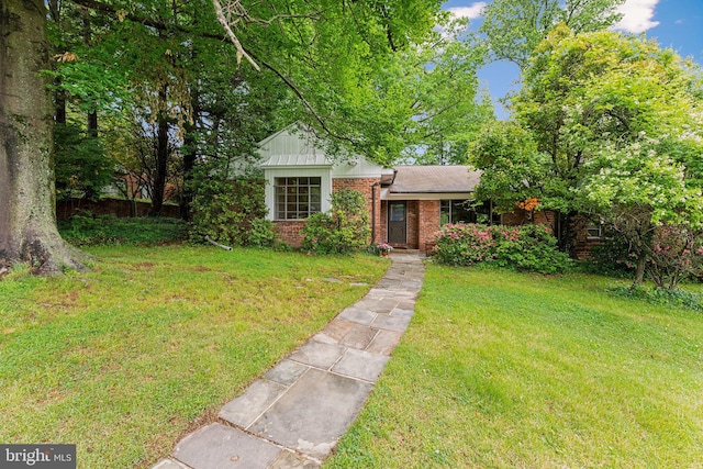 view of front of house featuring brick siding, a front yard, and board and batten siding