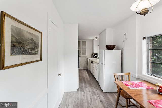 kitchen featuring freestanding refrigerator, light wood finished floors, white cabinetry, and light countertops