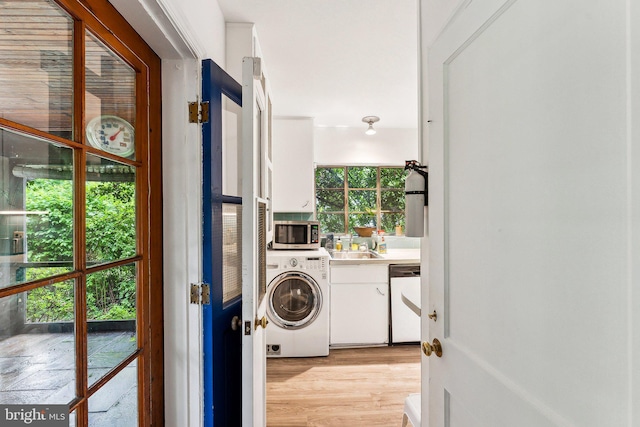 clothes washing area with washer / clothes dryer, cabinet space, and light wood-style flooring
