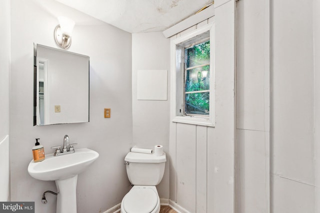 bathroom with toilet, a sink, and baseboards