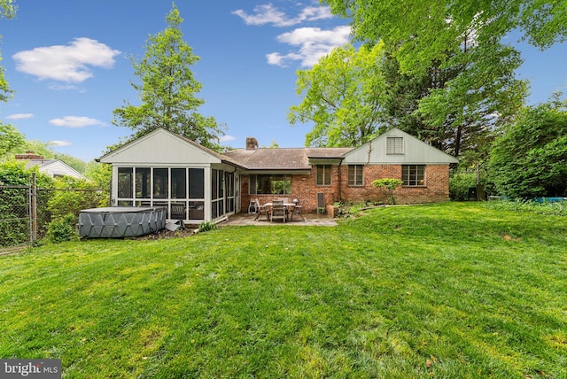 rear view of property with a sunroom, a patio area, brick siding, and a chimney