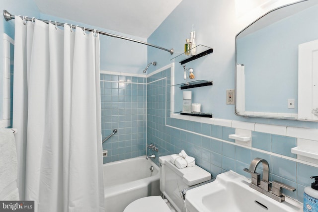 full bathroom with a sink, shower / tub combo, toilet, and tile walls