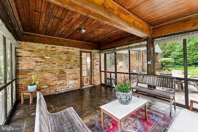 sunroom with brick wall, wood ceiling, healthy amount of natural light, and beamed ceiling