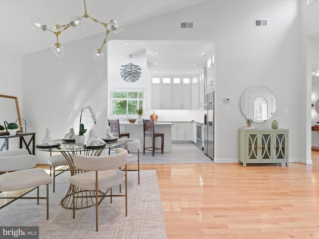 dining space with high vaulted ceiling, light wood finished floors, baseboards, and recessed lighting