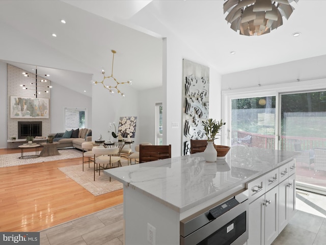 kitchen with high vaulted ceiling, a chandelier, recessed lighting, white cabinetry, and light stone counters