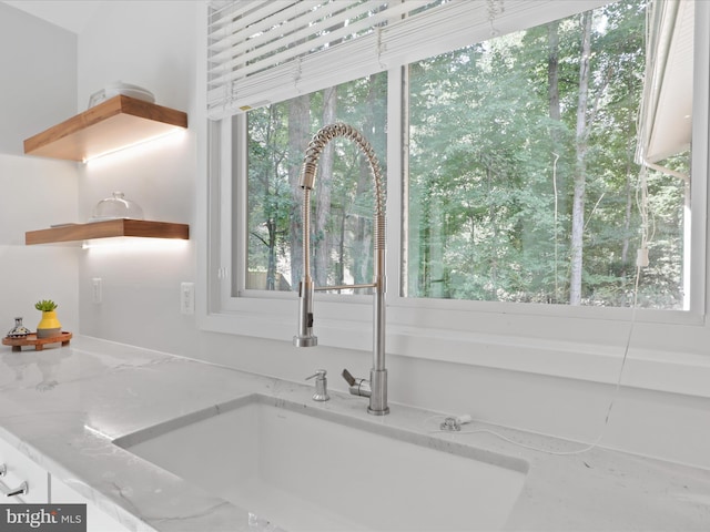 kitchen view of a sink, open shelves, and light stone counters
