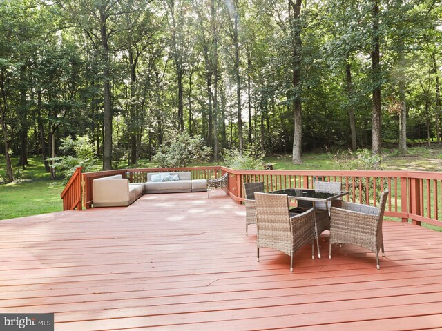 wooden terrace with outdoor dining area, an outdoor living space, and view of wooded area