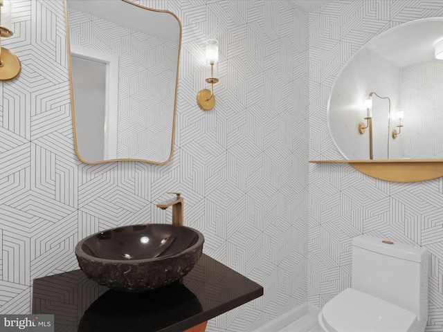 half bathroom featuring toilet and wallpapered walls