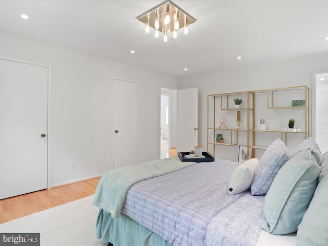 bedroom featuring wood finished floors, recessed lighting, a chandelier, and connected bathroom