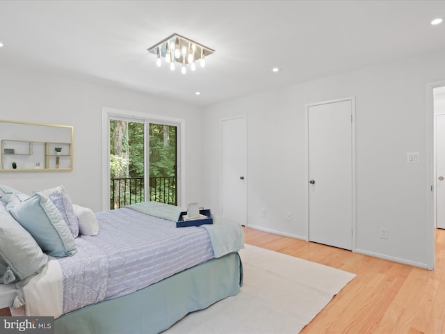 bedroom featuring wood finished floors, recessed lighting, baseboards, access to exterior, and multiple closets