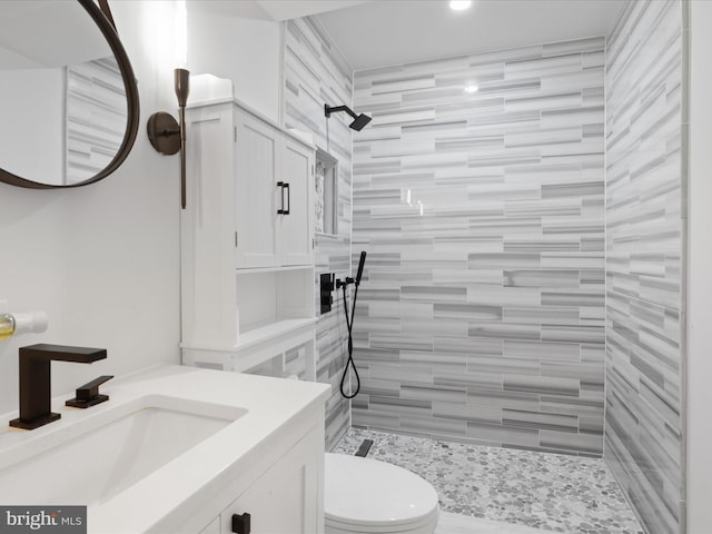 full bathroom featuring a tile shower, toilet, vanity, and recessed lighting