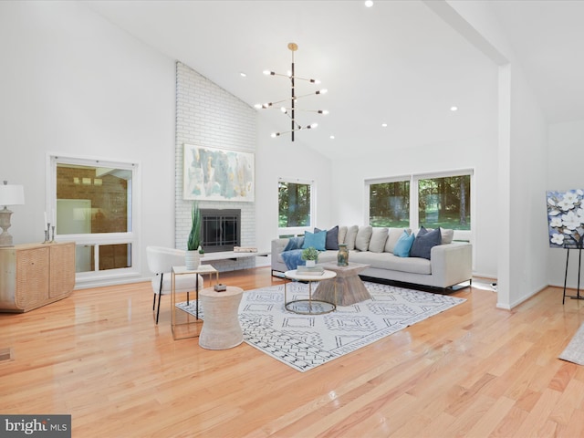 living area featuring high vaulted ceiling, a fireplace, wood finished floors, a chandelier, and recessed lighting