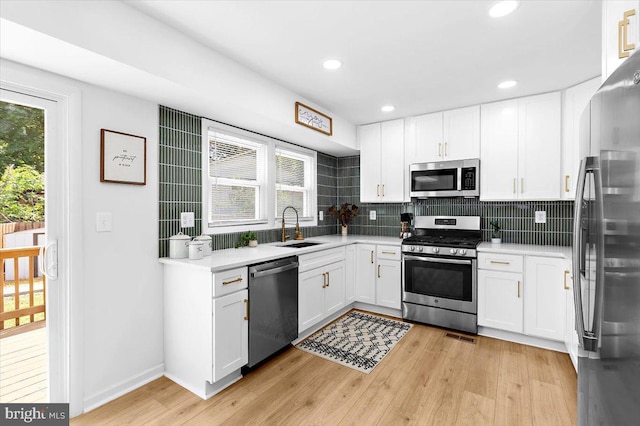 504 Kenora Dr, Millersville, MD 21108 - kitchen featuring appliances with stainless steel finishes, a sink, backsplash, light countertops, and light wood-type flooring