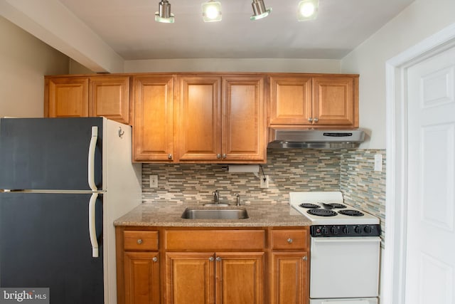 kitchen featuring freestanding refrigerator, electric range, under cabinet range hood, a sink, and backsplash