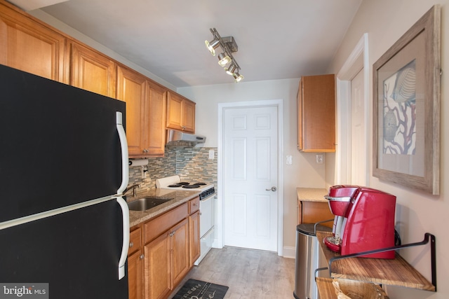 kitchen featuring freestanding refrigerator, white electric range oven, a sink, under cabinet range hood, and light wood-style floors