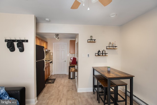 hallway featuring light wood-style floors, baseboards, and a baseboard heating unit