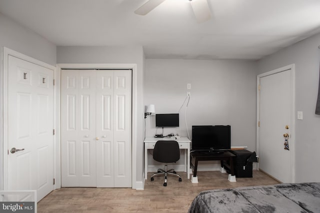 bedroom with an office area, light wood-style floors, a closet, a ceiling fan, and baseboards
