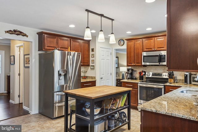 kitchen featuring appliances with stainless steel finishes, tasteful backsplash, recessed lighting, light stone countertops, and pendant lighting