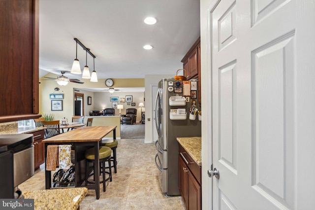 kitchen with a ceiling fan, freestanding refrigerator, open floor plan, butcher block counters, and hanging light fixtures