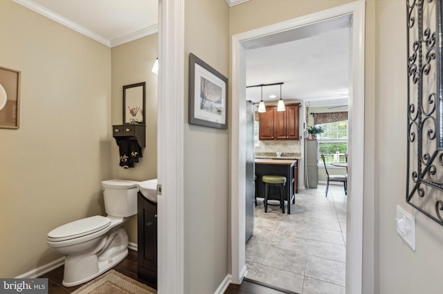 bathroom featuring vanity, crown molding, toilet, baseboards, and tasteful backsplash