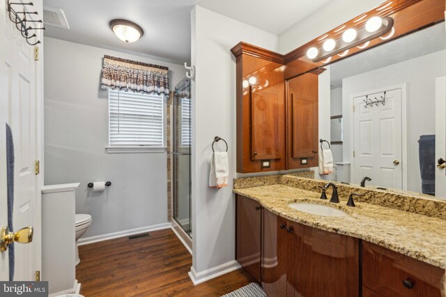 full bath featuring wood finished floors, baseboards, vanity, toilet, and a shower stall