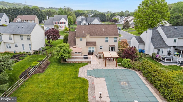 rear view of property featuring a residential view, a covered pool, and a patio area