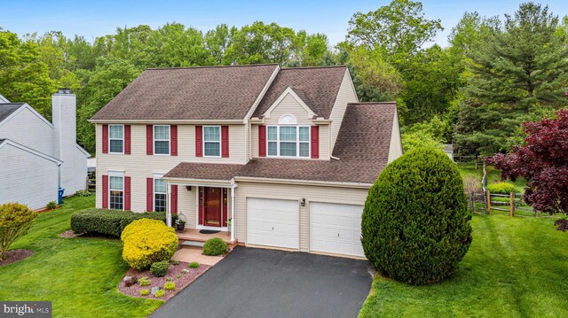 view of front of property with asphalt driveway, an attached garage, and roof with shingles