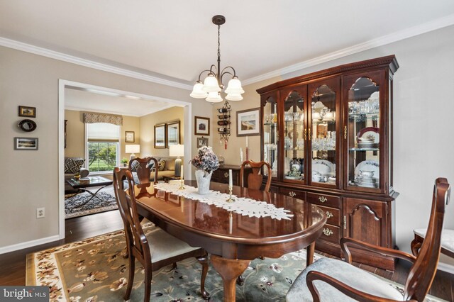 dining space with ornamental molding, wood finished floors, a chandelier, and baseboards
