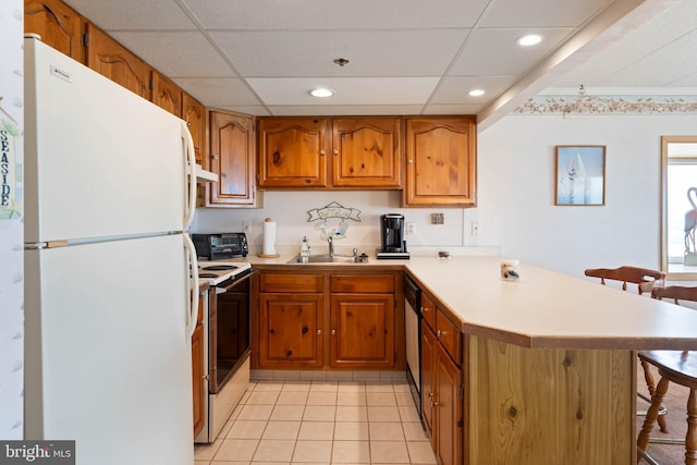 6109 Atlantic Ave Unit 201, Ocean City, MD 21842 - kitchen with white appliances, a peninsula, a breakfast bar area, light countertops, and brown cabinets
