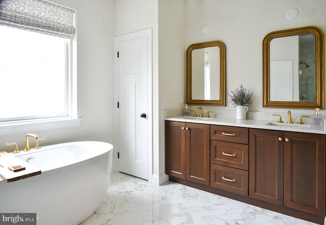 full bathroom featuring plenty of natural light, marble finish floors, a freestanding bath, and double vanity