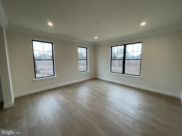 spare room with wood finished floors, baseboards, ornamental molding, and recessed lighting