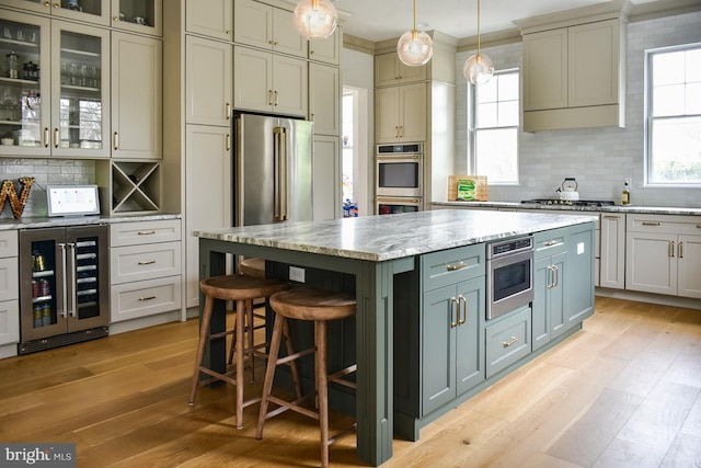 kitchen featuring wine cooler, appliances with stainless steel finishes, light wood-style flooring, and tasteful backsplash