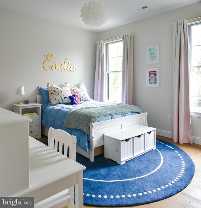 bedroom featuring multiple windows, baseboards, and wood finished floors