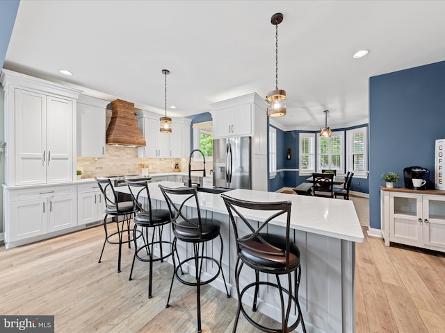 30106 Pelican Beach Cir, Dagsboro, DE 19939 - kitchen with stainless steel refrigerator with ice dispenser, custom exhaust hood, white cabinets, a center island with sink, and recessed lighting