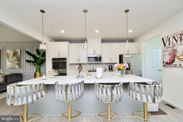 10810 Norbourne Farm Rd, Upper Marlboro, MD 20772 - kitchen with stainless steel appliances, light wood-style flooring, white cabinets, a large island with sink, and backsplash