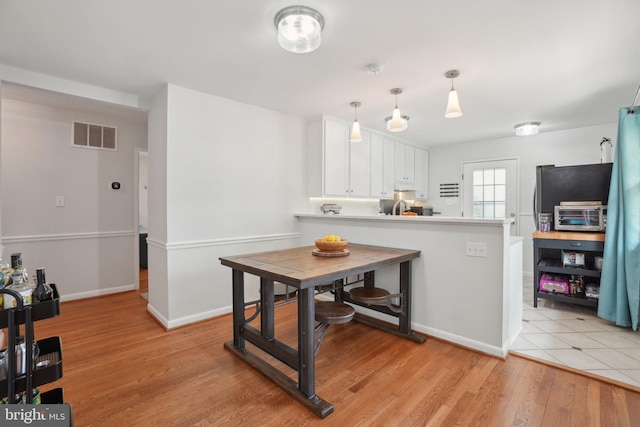 5728 Sunbury Dr, Alexandria, VA 22303 - kitchen featuring white cabinets, light wood-style floors, a peninsula, light countertops, and baseboards