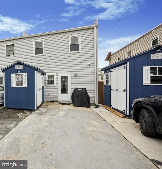 back of property featuring a storage unit, an outdoor structure, and a patio