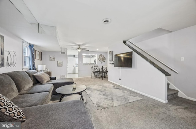 living area with stairway, carpet, a ceiling fan, and baseboards