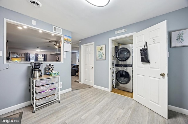 washroom featuring stacked washer / dryer, wood finished floors, ceiling fan, and baseboards