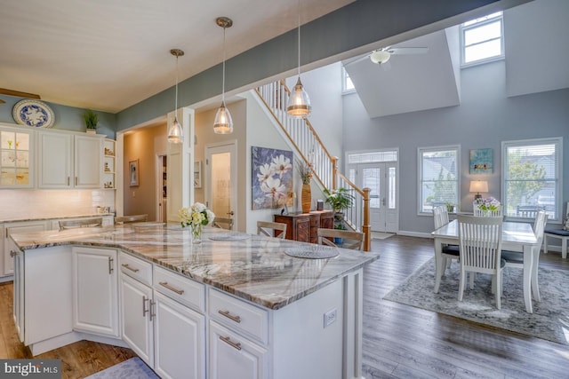 kitchen with healthy amount of natural light, a ceiling fan, a high ceiling, and white cabinetry