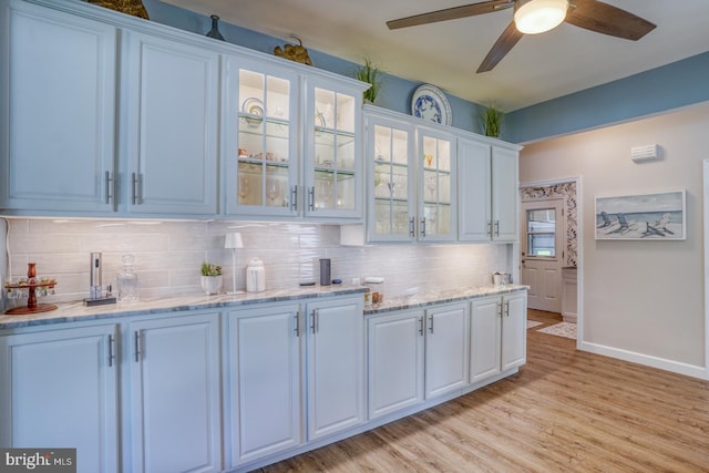 bar with tasteful backsplash, a ceiling fan, light wood finished floors, and baseboards