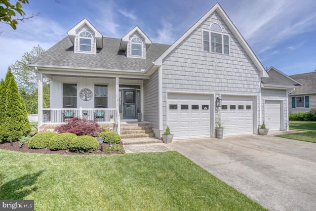 new england style home with driveway, a porch, a shingled roof, and a front yard