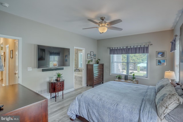 bedroom with wood finished floors, connected bathroom, a ceiling fan, and baseboards