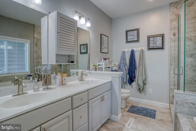 bathroom with a tile shower, double vanity, toilet, and baseboards