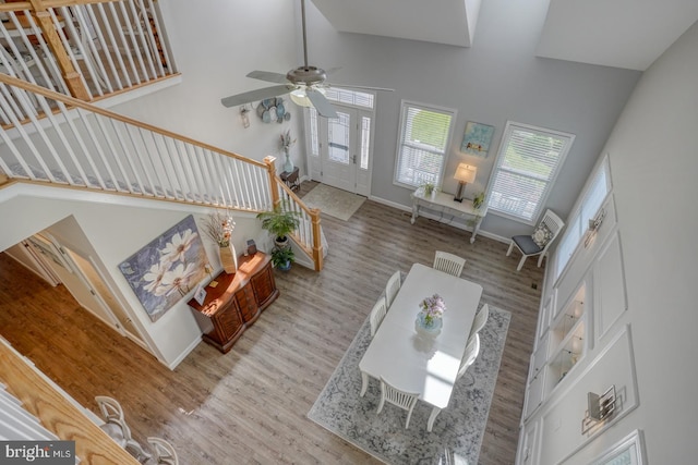 living area featuring stairs, high vaulted ceiling, wood finished floors, ceiling fan, and baseboards